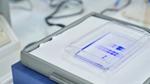 Close-up of a laboratory gel electrophoresis setup with illuminated blue sample bands.